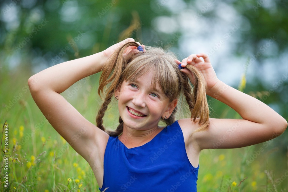 Obraz premium School-age girl in a blue dress with two long braids.