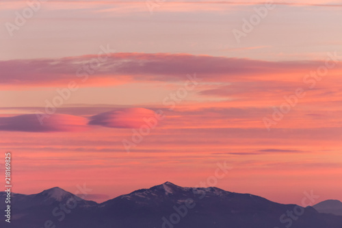 A view of some mountains top, beneath a beautiful, warm colored sky at sunset