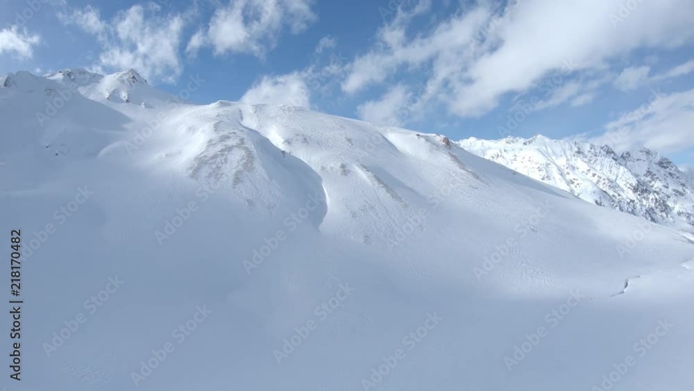 Aerial view of white winter mountains with snow, clouds and blue sky. Shot flat raw for post color grading. Ischgl. Austria. Alps Aerial view of white winter mountains with snow, clouds and blue sky. Shot flat raw for post color grading. Ischgl. Austria. Alps
