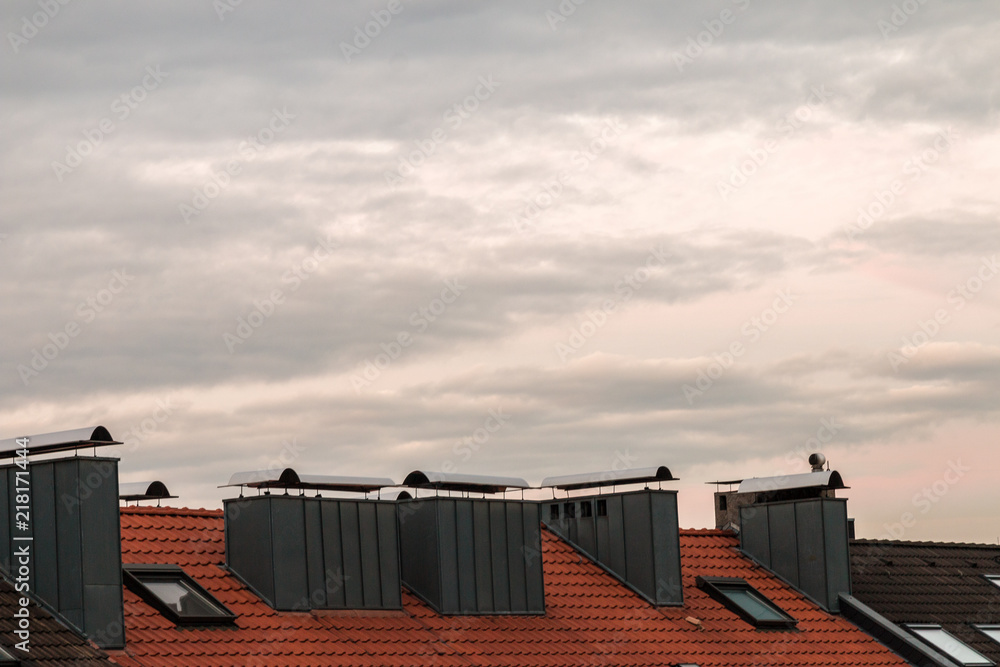 Roofs with chimneys and dramatic sky