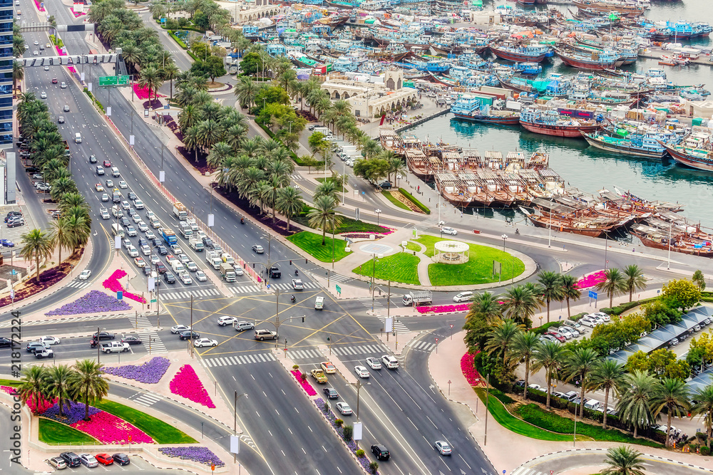 Fototapeta premium Road intersection and port in Deira city center in Dubai, UAE. Aerial view on crossroads with city traffic and boats.