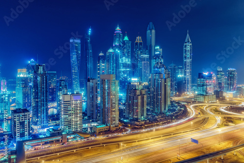 Scenic nighttime skyline of big modern city with illuminated skyscrapers. Aerial view of Dubai Marina  UAE. Multicolored travel background.