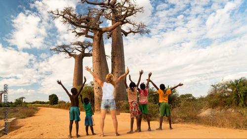 woman exult with black children and greating a baobab tree, concept of african united