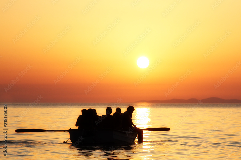 Familie auf Schlauchboot paddelt in den Sonnenuntergang