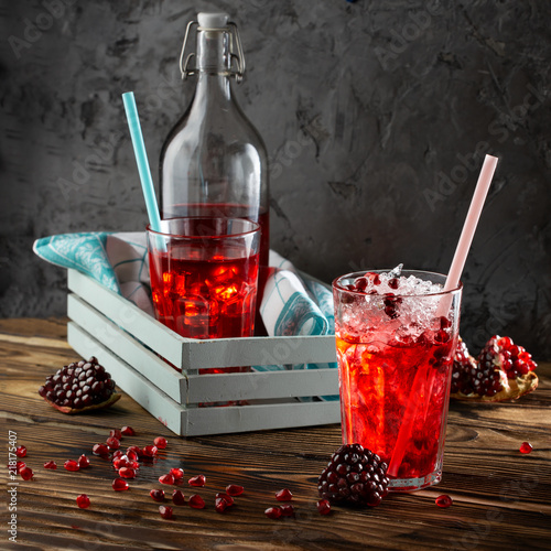 Pomegranate juice with ice in a decanter and a jar on a dark wooden background. Rustic style. photo