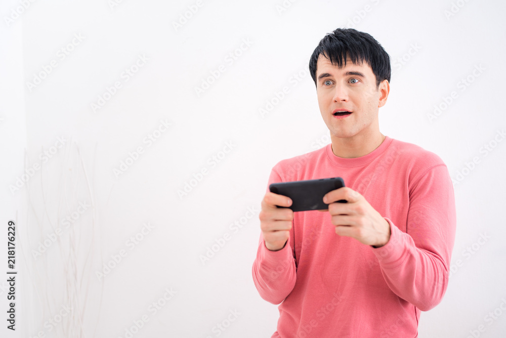Handsome man using smart phone with white wall background Handsome man using smart phone with white wall background