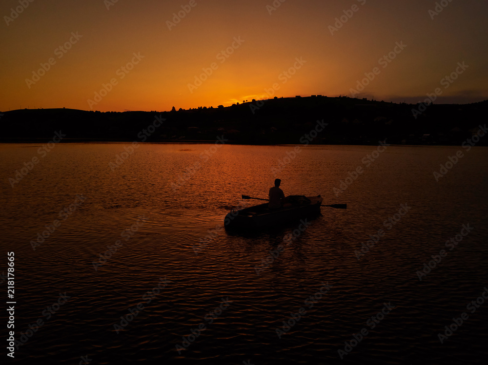 Lonely guy sitting in a boat at sunset. 