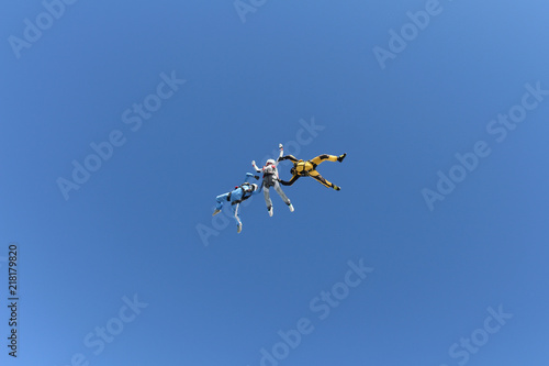 Skydiving. Two instructors are training a student to fly.