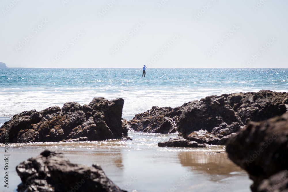 A solitary paddle-boarder out on the ocean.