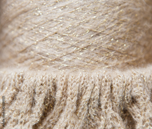 Nude and gold colour spool of thread on the knitted textile background