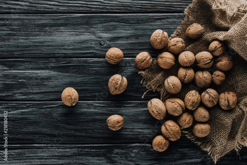  walnuts in nutshells with sackcloth on dark wooden surface