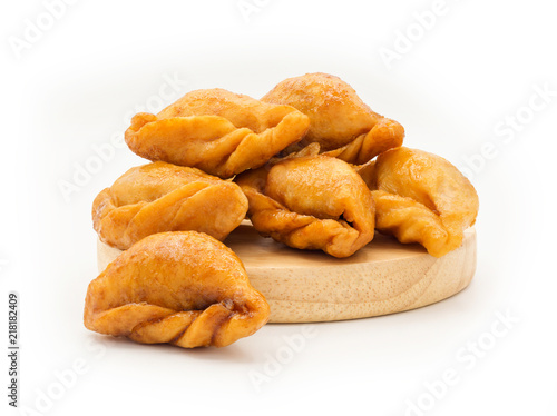 Packshot close up view of "Pan Klib" traditional mini Thai puff dessert stuffed material with fish, curry, shallot, pepper seasoned sugar and salt on wood plate isolate on white background