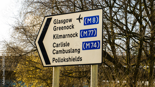 Road directional sign for Glasgow airport, Greenock, Kilmarnock, and Carlisle.