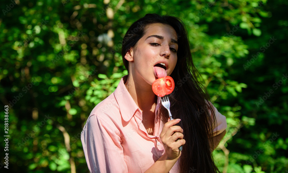 Girl holds fork with juicy ripe tomato. Lady attractive brunette eats  tomato. Seductive appetite. Her appetite is sexy. Girl seductive eats red  vegetable. Woman full of desire hungry eating tomato foto de