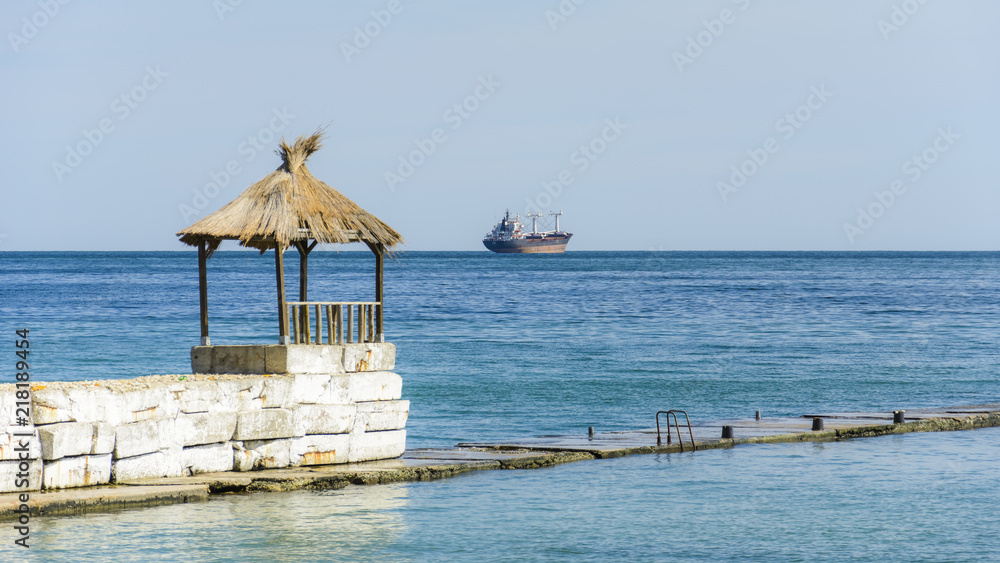Fototapeta premium Hut in a pier with a tanker in the horizon.