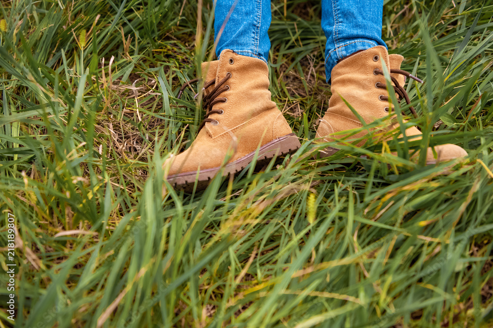 cropped shot of childish legs in boots on green grass