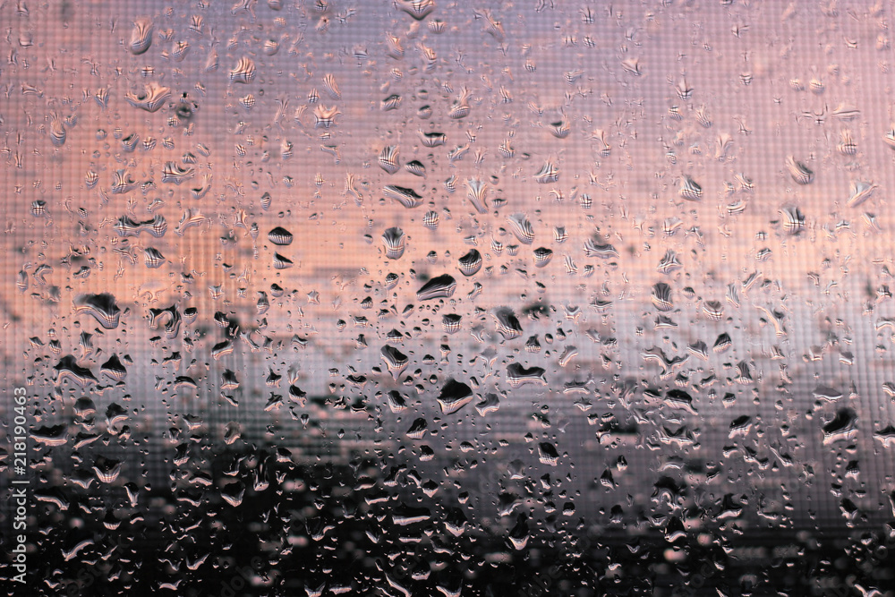 Pure raindrops on a window with mosquito net surface on a sunset clouds background. Water drops pattern close up shot Pure raindrops on a window with mosquito net surface on a sunset clouds background. Water drops pattern close up shot
