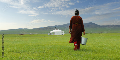 Mongolian farmer carrying bucket of milk after milking cow in the grassland of Mongolia