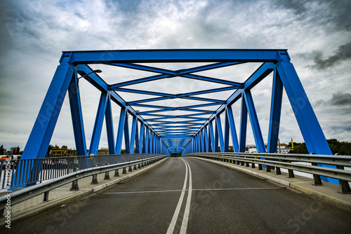 Fototapeta Naklejka Na Ścianę i Meble -  Blue metal bridge with clouds in the background.