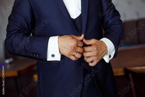 the man closes the button on the jacket.  meeting of the groom.  a man wears a jacket © mihail_pustovit