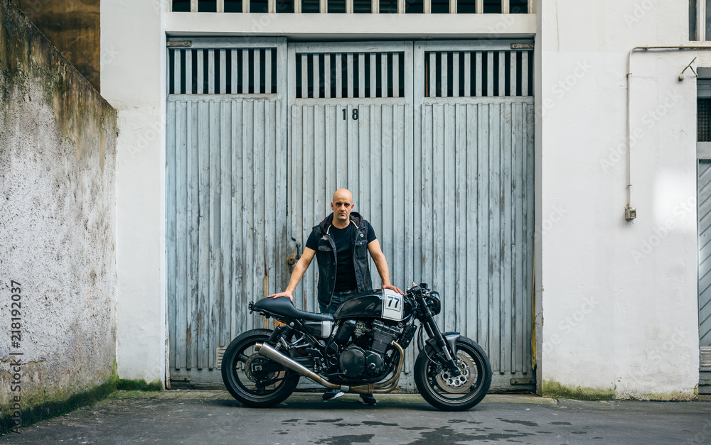 Builder posing with a custom motorcycle in front of the garage door
