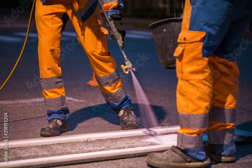 Traffic line painting. Workers are painting white street lines on pedestrian crossing 