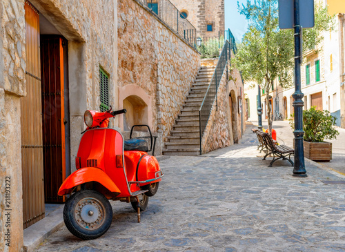 vintage red motor scooter parked on cobbled street in hostoric spanish village photo