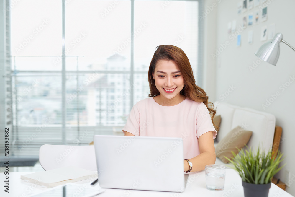 Portrait of a cheerful businesswoman sitting at the table in office and looking at camera Portrait of a cheerful businesswoman sitting at the table in office and looking at camera