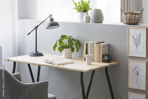 Принти на полотні Real photo of wooden desk with fresh plant, black lamp, coffee cup and books sta