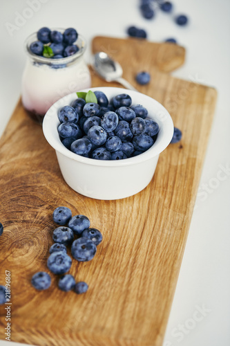 close up view of fresh blueberries and yogurt for breakfast on wooden cutting board