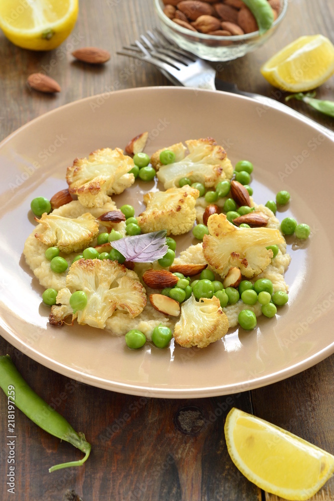 Salad with roasted cauliflower and green peas, almonds served on vegetable puree, vertical Salad with roasted cauliflower and green peas, almonds served on vegetable puree, vertical