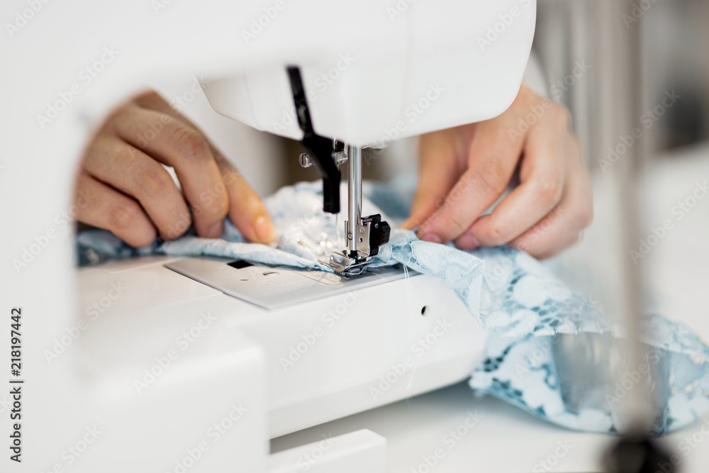 A woman is sewing with the electric sewing-machine. Fashion, tailor's workshop.