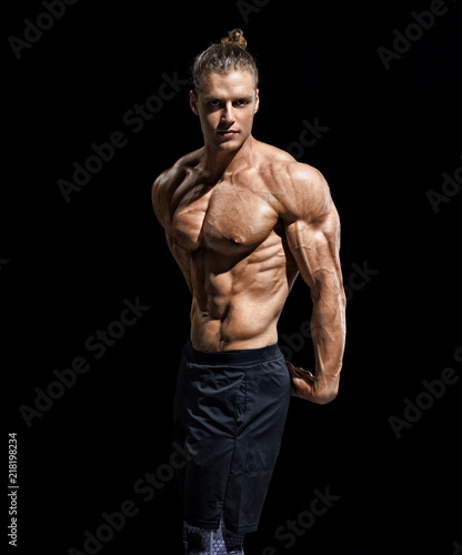 Bodybuilder showing off his muscular physique on black background. Strength and motivation