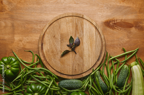 Organic raw green vegetables with round board on wooden table