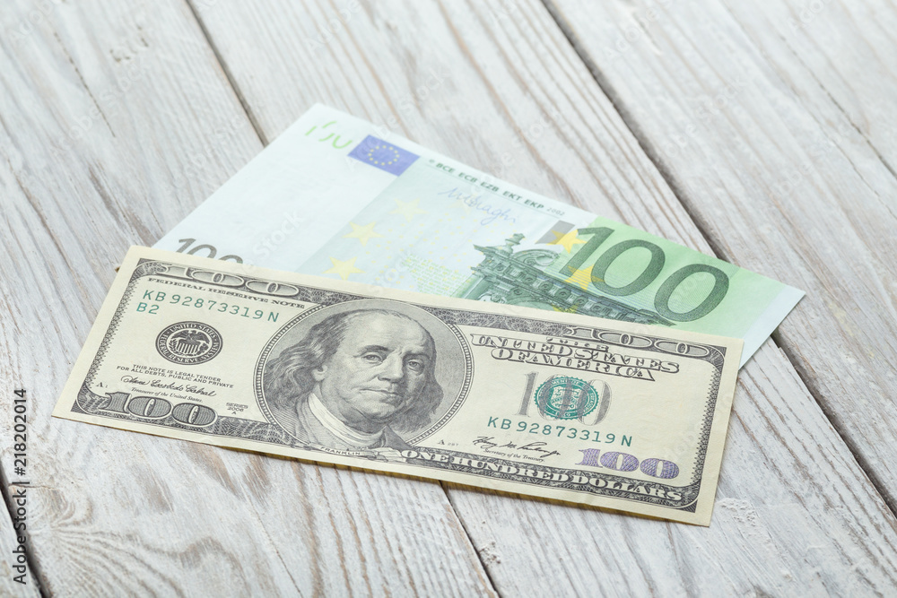 A hundred dollars and one hundred euros are on a white wooden table. Money, bills of one hundred dollars and a hundred euros on a light background. Banknotes. Money. A hundred dollars and one hundred euros are on a white wooden table. Money, bills of one hundred dollars and a hundred euros on a light background. Banknotes. Money.