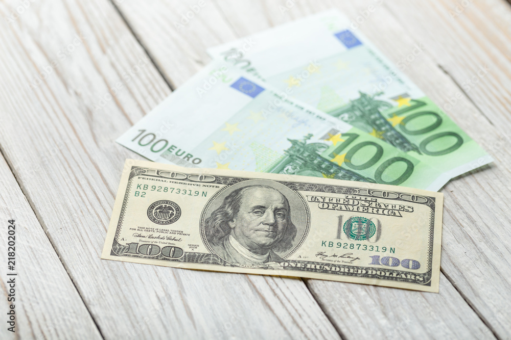 A hundred dollars and one hundred euros are on a white wooden table. Money, bills of one hundred dollars and a hundred euros on a light background. Banknotes. Money. A hundred dollars and one hundred euros are on a white wooden table. Money, bills of one hundred dollars and a hundred euros on a light background. Banknotes. Money.