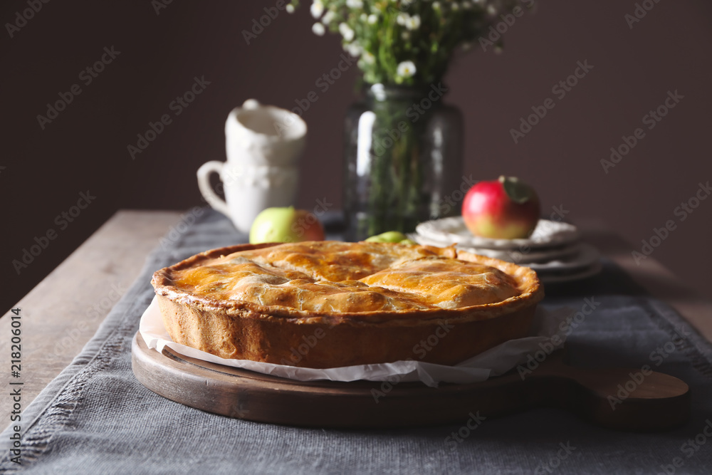 Board with delicious apple pie on table