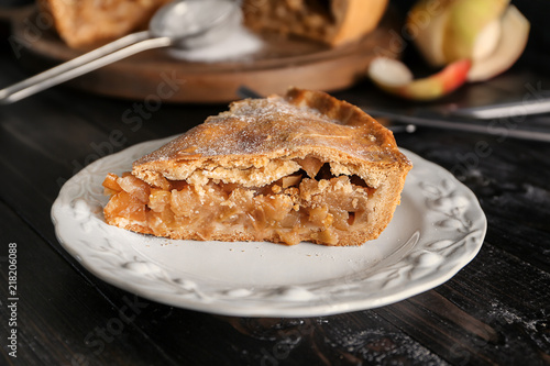 Plate with piece of tasty apple pie on table