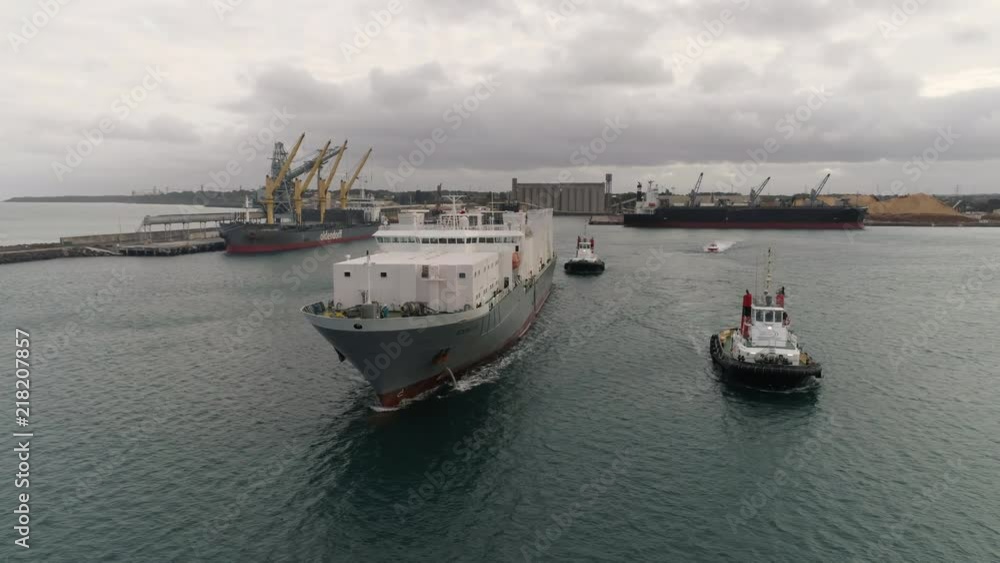 Livestock ship leaving port assisted by two tug boats. Livestock ship leaving port assisted by two tug boats.