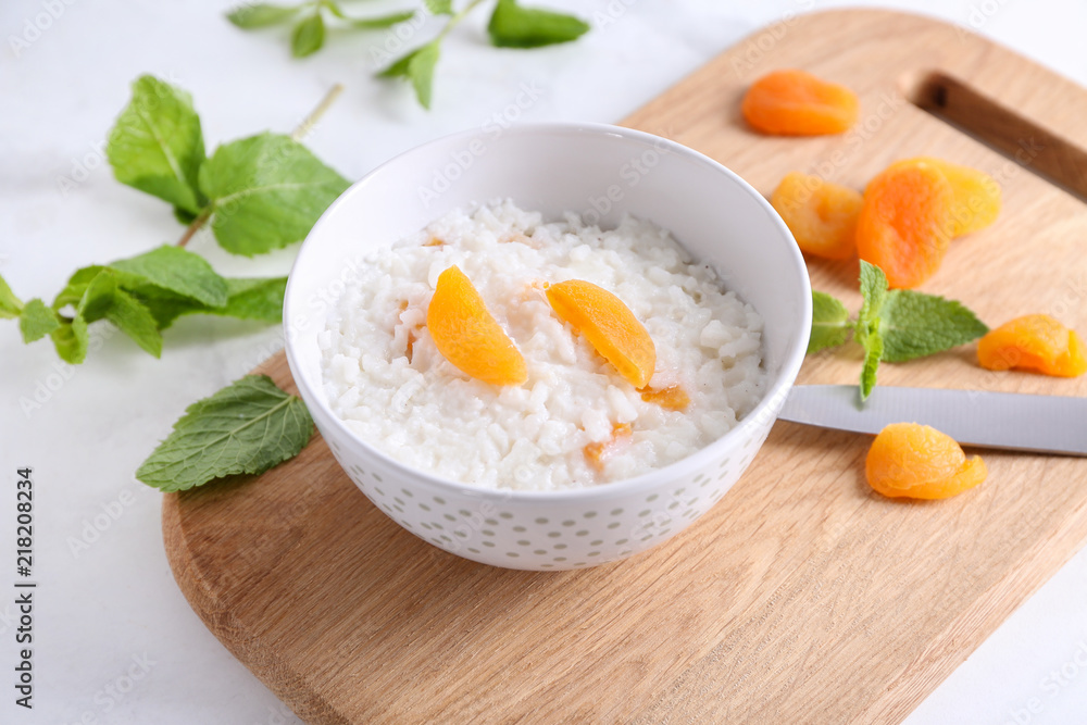 Bowl with delicious rice pudding and dried apricot on board Bowl with delicious rice pudding and dried apricot on board