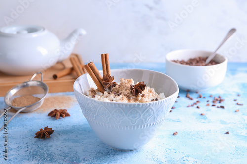 Bowl with delicious rice pudding and cinnamon powder on light table