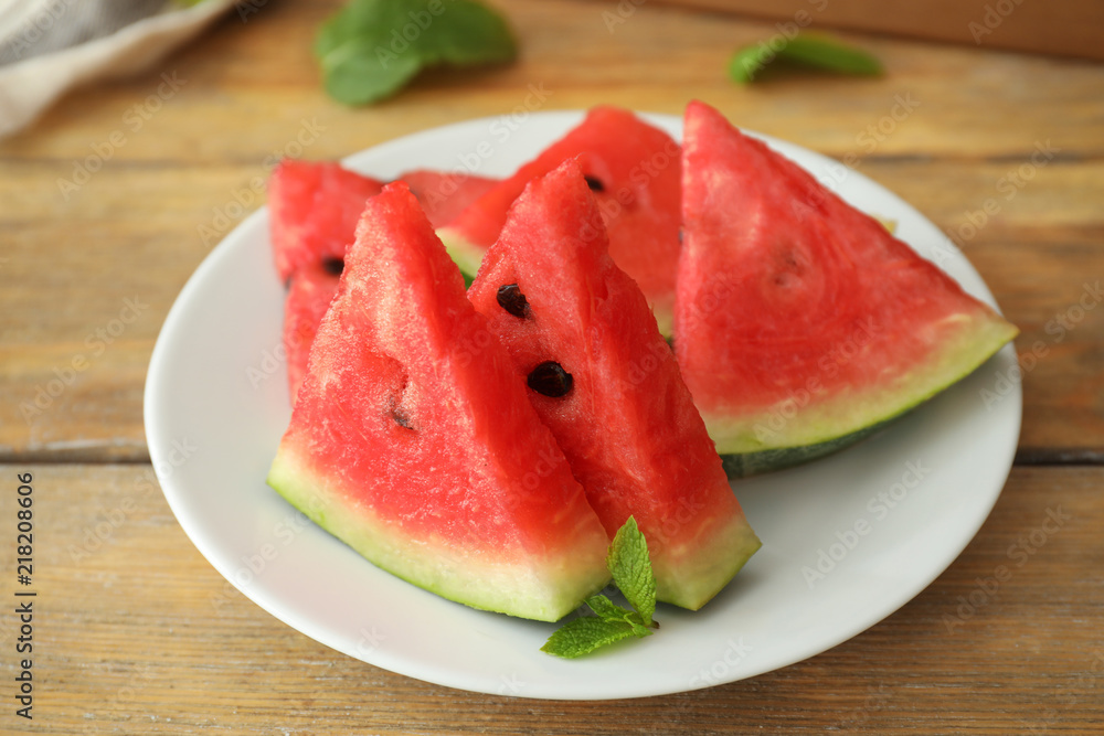 Plate with sweet watermelon slices on wooden table