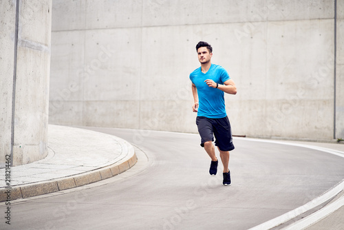 Jogging in the city. Picture of muscular man sprinting during outdoor workout