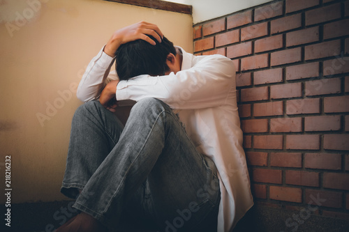 Depressed man sitting head in hands on the stairs in building. with low light environment, dramatic concept, concept of Major depressive disorder, unemployed, sadness, depressed and human problems, photo