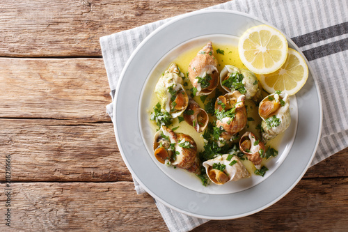 French cuisine: sea snails bulot with garlic sauce and lemon close-up. horizontal top view from above