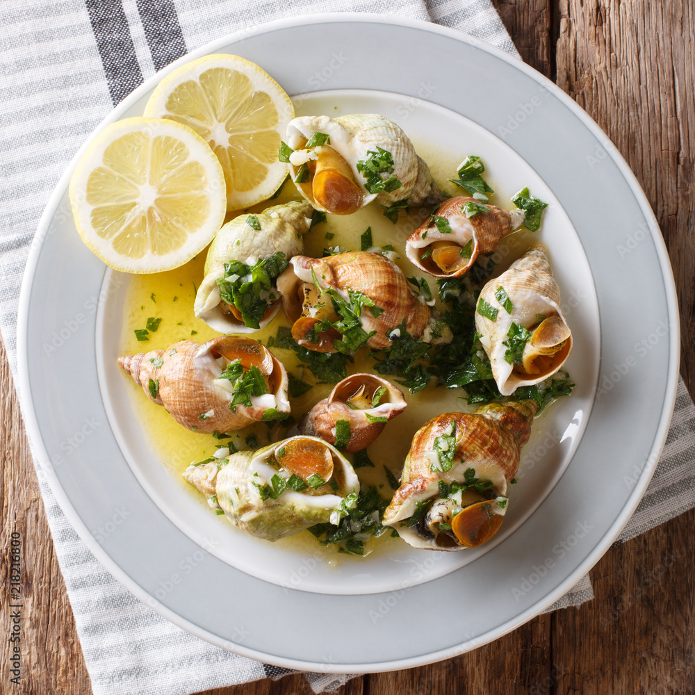 Bulots Cuits - Cooked Waved Whelks with a sauce of butter, garlic and parsley, lemon close-up. top view from above Bulots Cuits - Cooked Waved Whelks with a sauce of butter, garlic and parsley, lemon close-up. top view from above