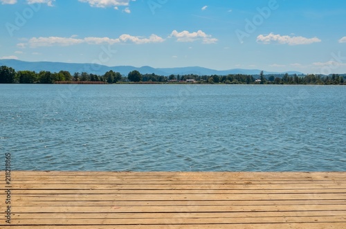 Beautiful autumnal landscape. Lake and mountains with wooden planks in the foreground.