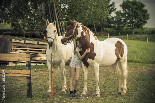 Young girl is standing between two horses / Young girl is standing smiling between two horses, a horse is hugged. © ub-foto