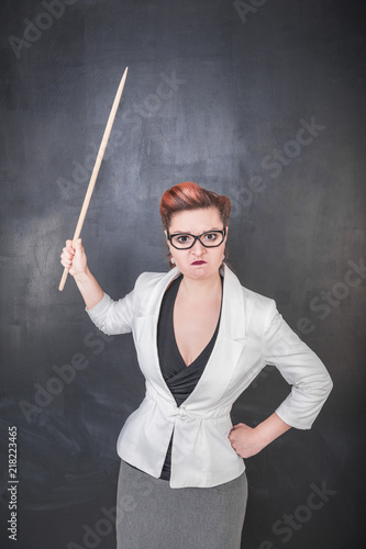 Angry teacher with pointer on the chalkboard background