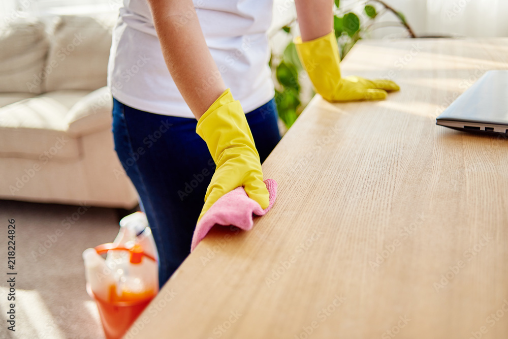 Cropped image of woman's hand in yellow rubber protective glove cleaning wooden tablel with pink rag, copy space, soft focuse. Housework, cleanig and chores concept. Cropped image of woman's hand in yellow rubber protective glove cleaning wooden tablel with pink rag, copy space, soft focuse. Housework, cleanig and chores concept.